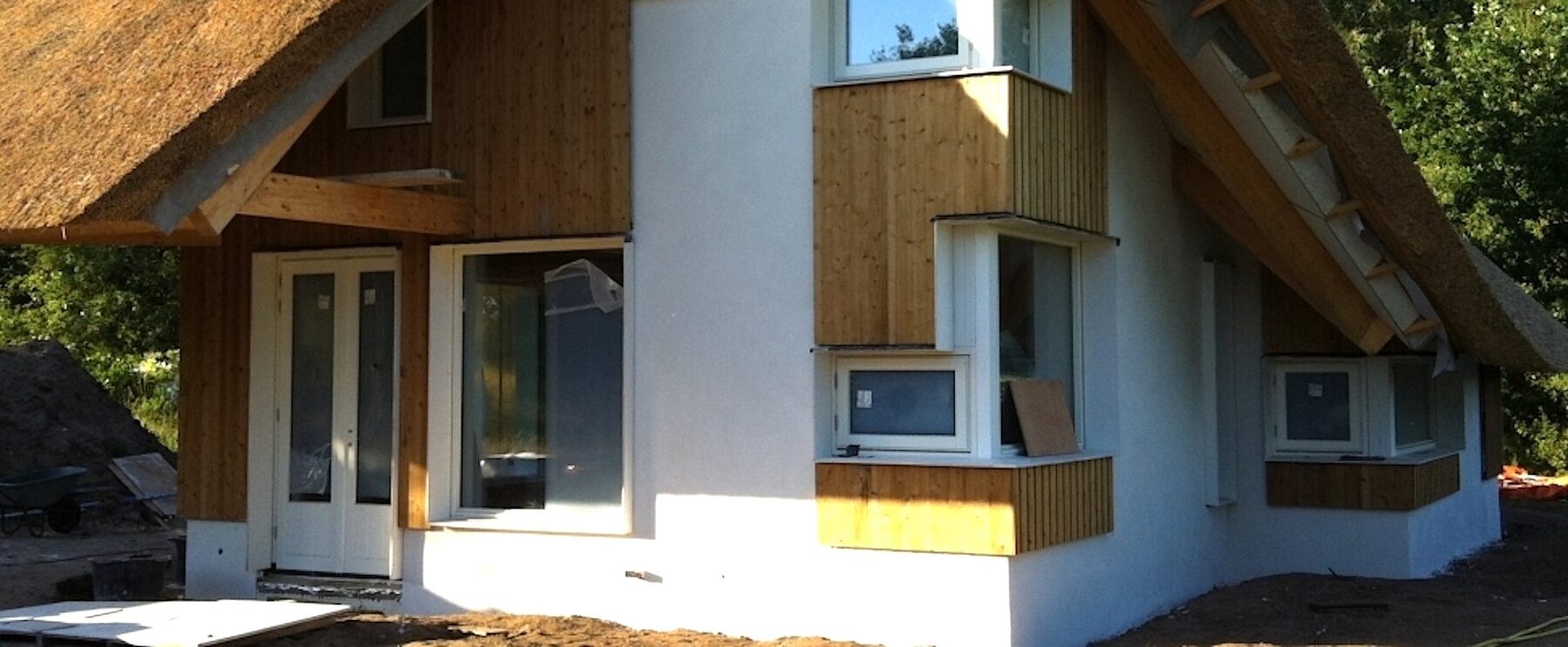 Wit gestuukte gevel van een woning met rieten dak
