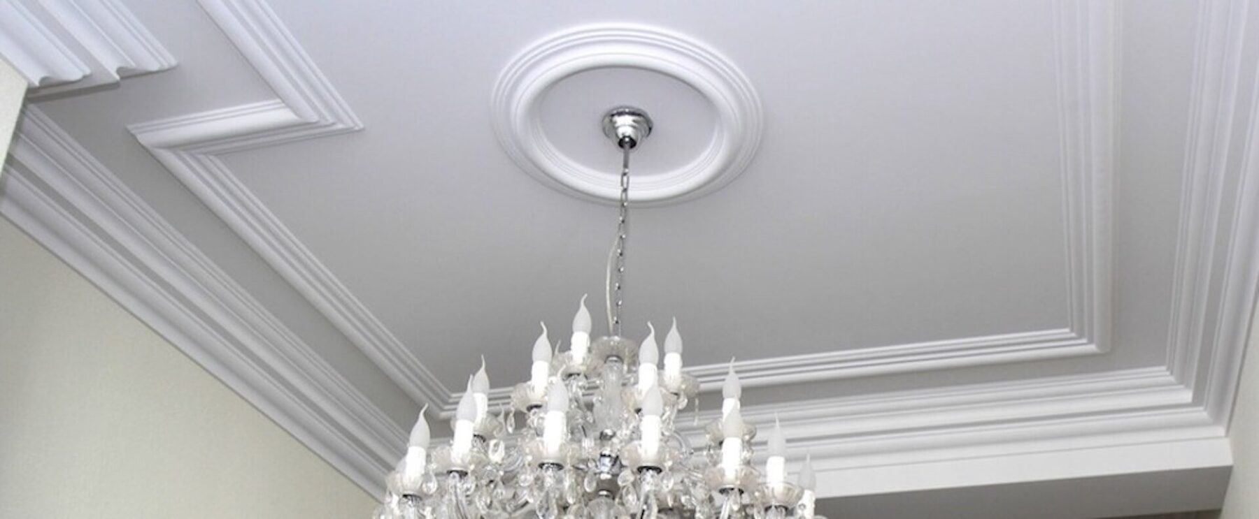 Plafond met sierlijsten en een rozet boven een kroonluchter